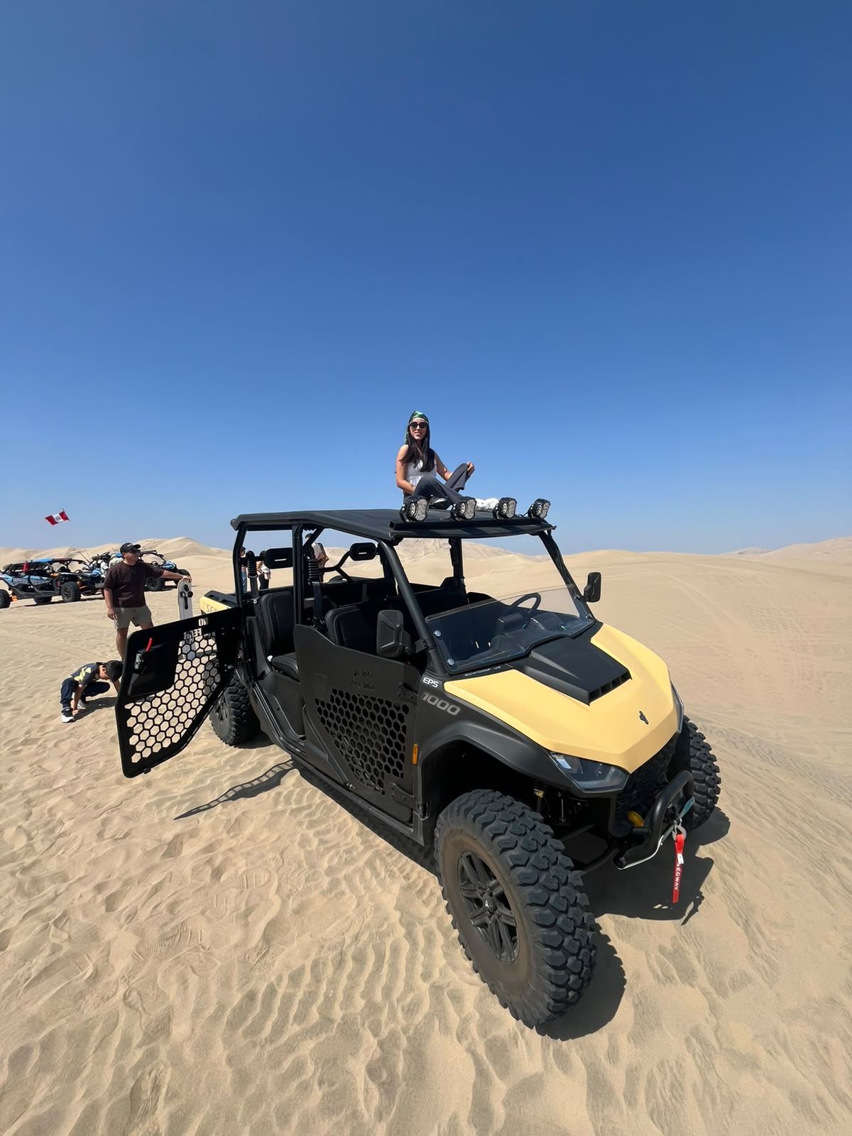 Group with a UTV, doors open, on the dunes of the Ica Desert