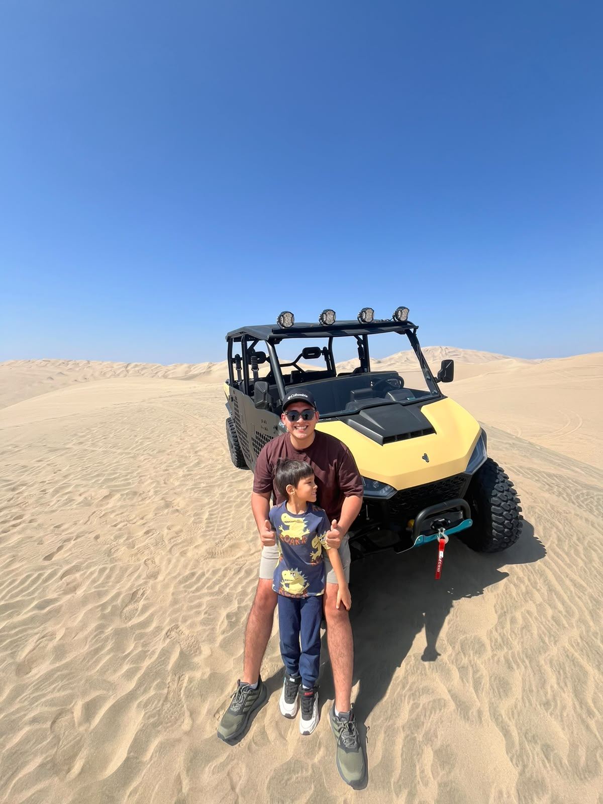Father and son beside a UTV in the middle of the Ica Desert